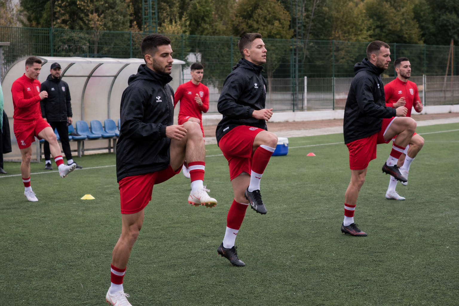 Jugadores amateur haciendo calentamiento dinámico en un campo municipal antes de la segunda jornada