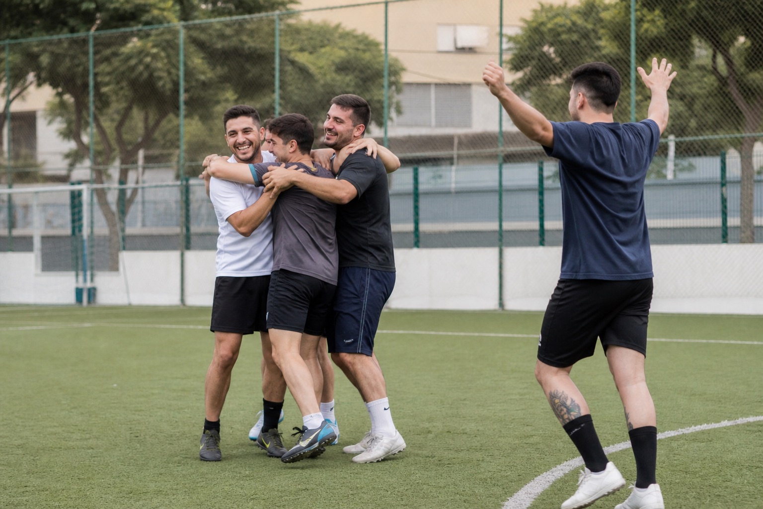 Jugadores de fútbol amateur celebrando un gol en un campo de barrio, ambiente de liga local entre amigos.