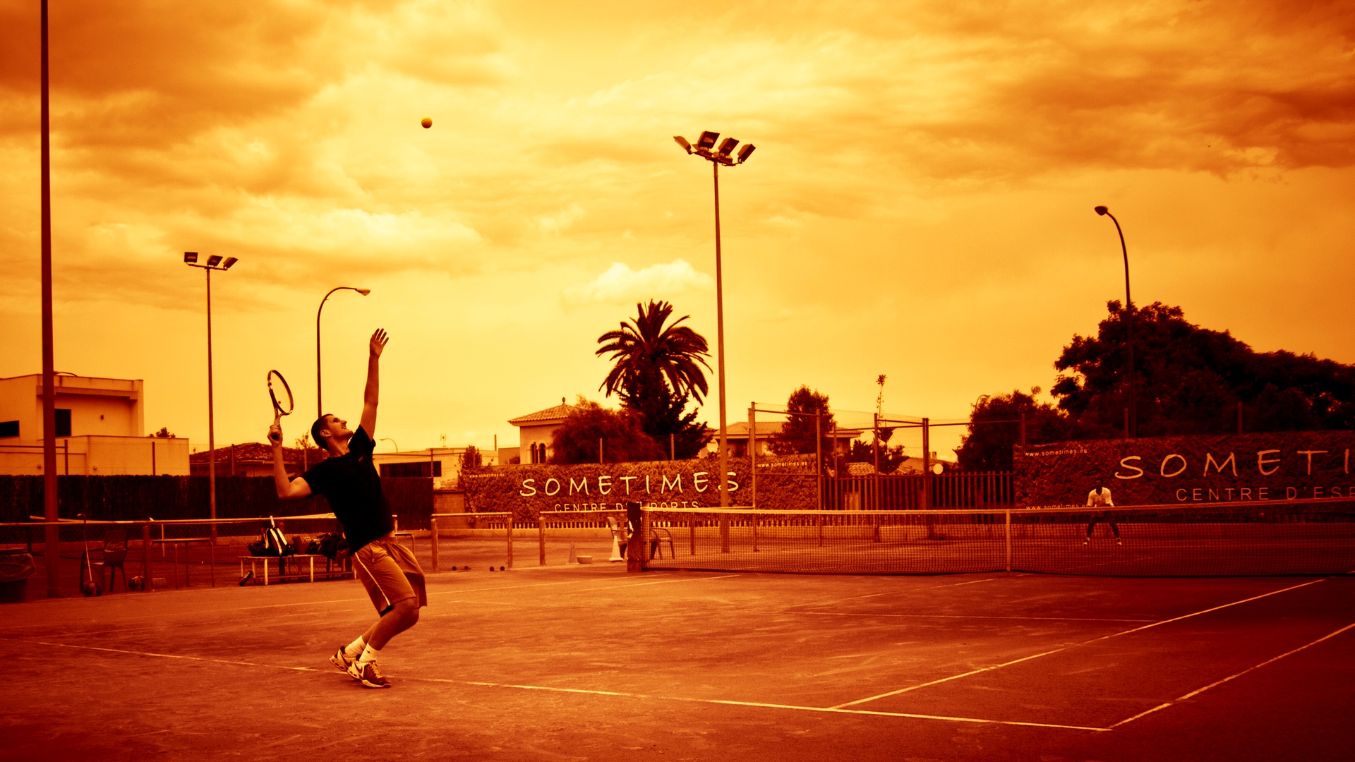Jugadores de tenis amateur en una pista de tierra batida a primera hora de la mañana, con luz dorada y sombras largas