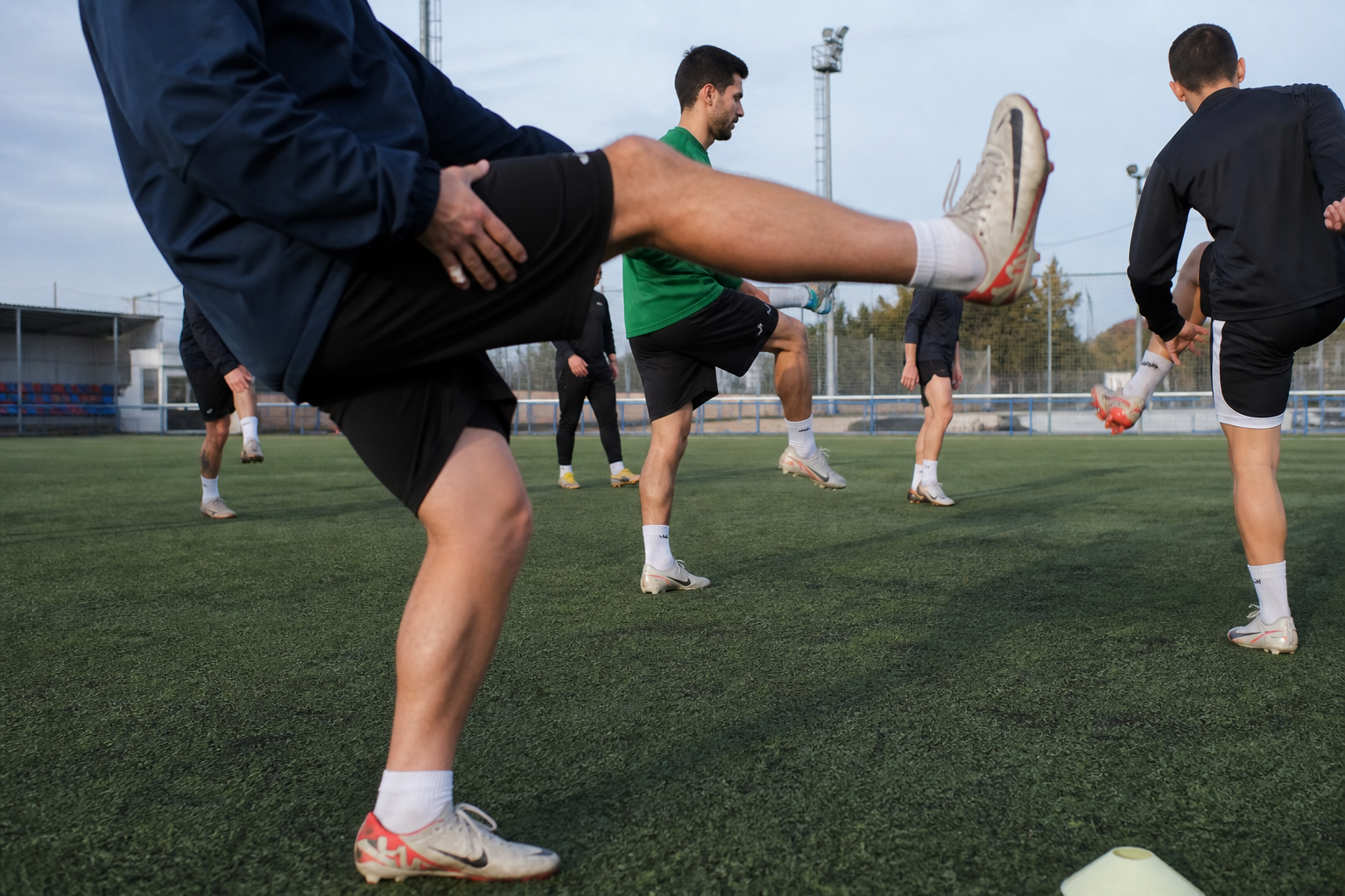 Jugadores de fútbol amateur haciendo estiramientos dinámicos antes del entrenamiento del martes