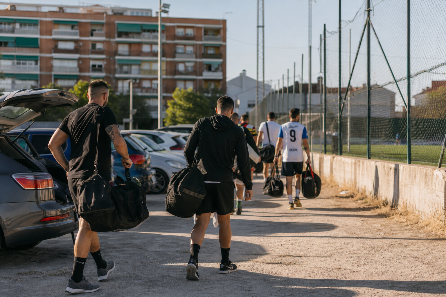 Jugadores amateur llegando a un campo municipal un domingo por la mañana con sus bolsas deportivas